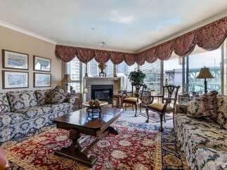 Experience luxurious living in this elegant living room, featuring a grand fireplace and plush, patterned sofas perfect for relaxation.