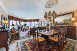 Experience elegant dining in this formal dining room, featuring a large, polished wood table surrounded by intricately carved chairs.