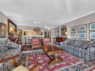 Step into this elegant living room, featuring a plush floral sofa and a matching armchair, perfect for relaxing.