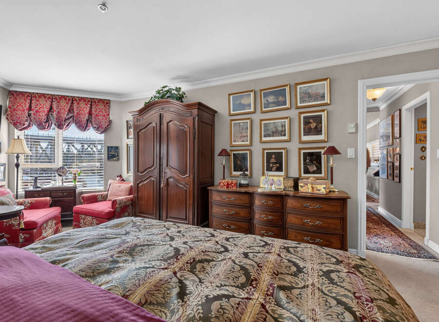 Step into this luxurious master suite, featuring a grand wooden armoire and a matching dresser adorned with ornate hardware.