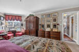 Step into this luxurious master suite, featuring a grand wooden armoire and a matching dresser adorned with ornate hardware.