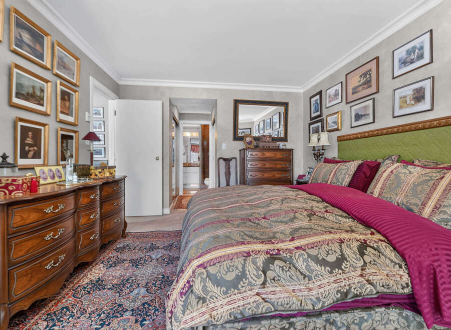 Step into this luxurious bedroom featuring a plush king-sized bed adorned with elegant bedding and a striking green tufted headboard.