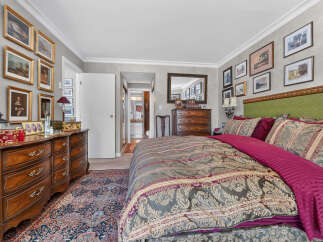Step into this luxurious bedroom featuring a plush king-sized bed adorned with elegant bedding and a striking green tufted headboard.