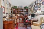 This home office features a large wooden desk with a computer and printer, complemented by a comfortable red and black office chair.