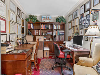 This home office features a large wooden desk with a computer and printer, complemented by a comfortable red and black office chair.