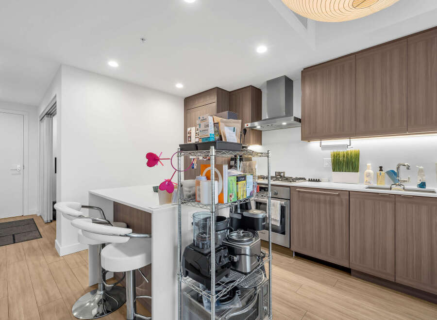 Experience modern living in this sleek kitchen featuring elegant wood cabinetry and a spacious island with bar seating.
