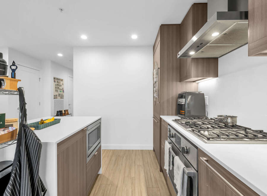Experience modern living in this stunning kitchen, featuring sleek wood cabinetry and a spacious island perfect for meal prep and casual dining.