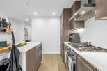 Experience modern living in this stunning kitchen, featuring sleek wood cabinetry and a spacious island perfect for meal prep and casual dining.