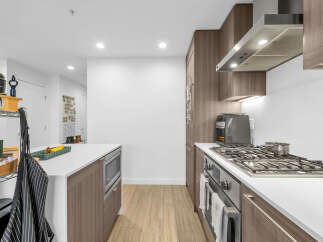 Experience modern living in this stunning kitchen, featuring sleek wood cabinetry and a spacious island perfect for meal prep and casual dining.