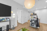 Experience modern living in this bright and airy apartment, featuring a sleek entertainment setup with a large flat-screen TV and a stylish floor lamp.