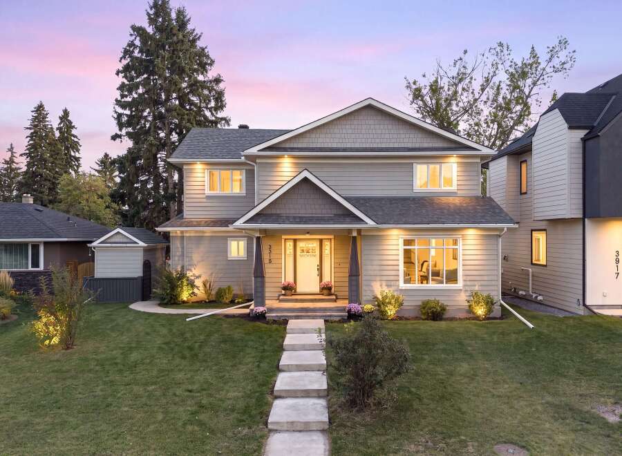 This stunning two-story home features a welcoming entrance with a white door and elegant landscaping.