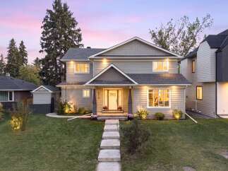 This stunning two-story home features a welcoming entrance with a white door and elegant landscaping.