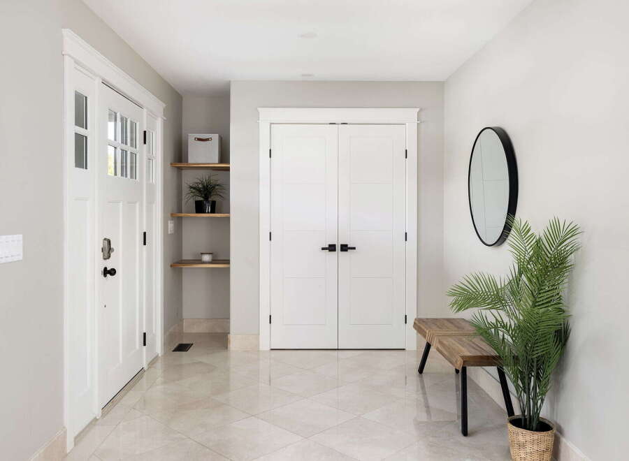 Step into this welcoming entryway featuring a bright white door with glass panes, complemented by sleek shelving for storage and decor.