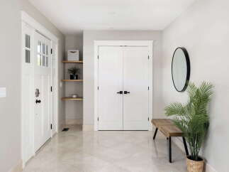 Step into this welcoming entryway featuring a bright white door with glass panes, complemented by sleek shelving for storage and decor.