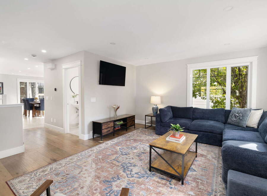 Step into this inviting living room, featuring a spacious sectional sofa perfect for gatherings and a large, ornate rug that adds warmth and character.