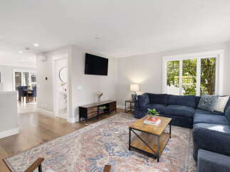 Step into this inviting living room, featuring a spacious sectional sofa perfect for gatherings and a large, ornate rug that adds warmth and character.