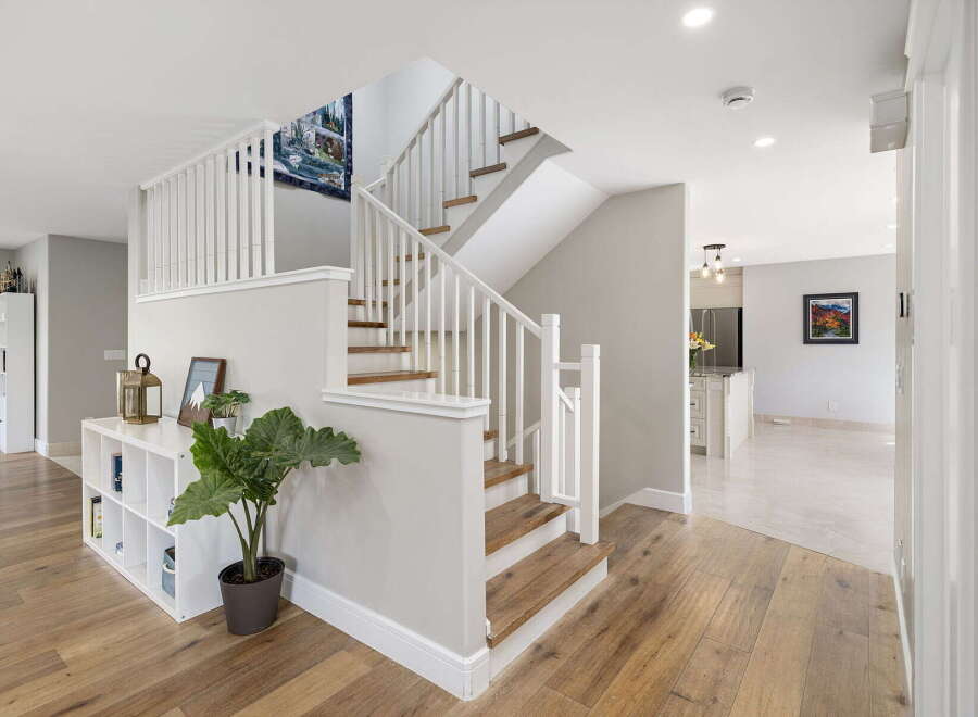 This inviting entryway features a stunning staircase with white railings and wooden treads, leading to the upper level.