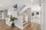 This inviting entryway features a stunning staircase with white railings and wooden treads, leading to the upper level.