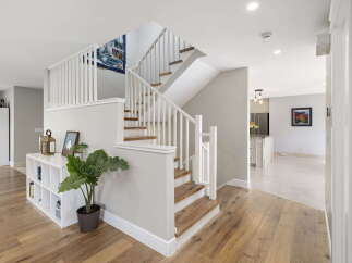 This inviting entryway features a stunning staircase with white railings and wooden treads, leading to the upper level.