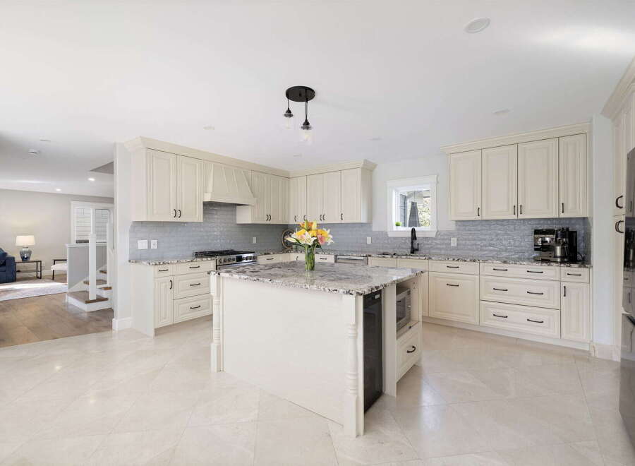 This stunning kitchen boasts elegant cream cabinetry complemented by a sleek gray subway tile backsplash.