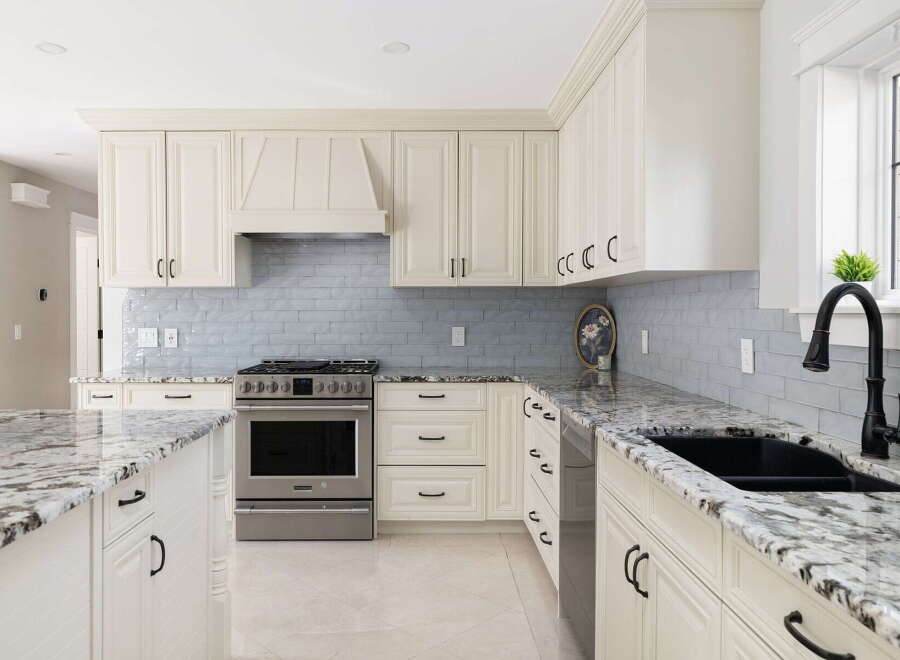Experience luxury in this stunning kitchen featuring elegant cream cabinetry and a sleek, modern backsplash.