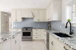 Experience luxury in this stunning kitchen featuring elegant cream cabinetry and a sleek, modern backsplash.