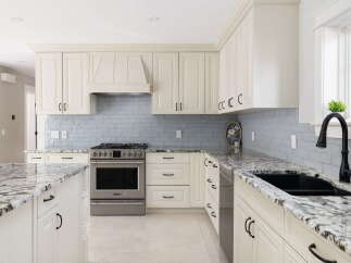 Experience luxury in this stunning kitchen featuring elegant cream cabinetry and a sleek, modern backsplash.