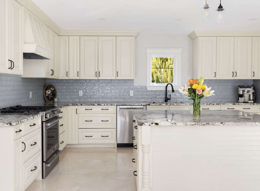 Experience the epitome of modern luxury in this stunning kitchen, featuring elegant cream cabinetry and a sleek grey subway tile backsplash.