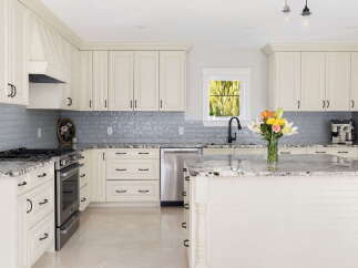 Experience the epitome of modern luxury in this stunning kitchen, featuring elegant cream cabinetry and a sleek grey subway tile backsplash.