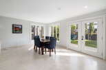 Enjoy bright and airy dining in this elegant space, featuring a large wooden table with comfortable upholstered chairs.