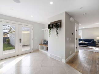 Step into a bright and airy entryway featuring elegant marble tile flooring and double glass doors that open to a lush green backyard.