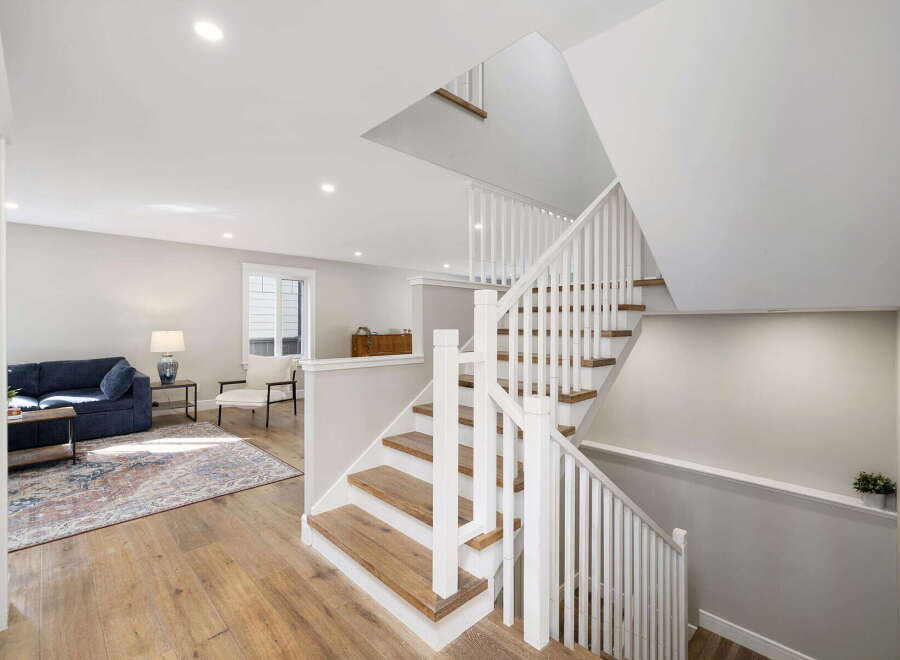 Step into this beautifully designed home featuring a modern open-concept living space with a comfortable navy sofa and elegant hardwood floors.