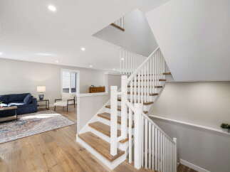 Step into this beautifully designed home featuring a modern open-concept living space with a comfortable navy sofa and elegant hardwood floors.