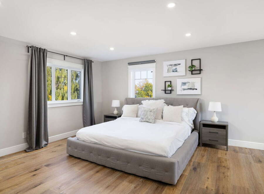Experience modern comfort in this serene bedroom, featuring a plush king-size bed with crisp white linens and an array of decorative pillows.
