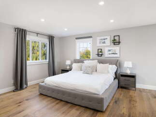 Experience modern comfort in this serene bedroom, featuring a plush king-size bed with crisp white linens and an array of decorative pillows.