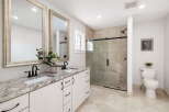 This modern bathroom features a spacious double vanity with granite countertops and elegant black fixtures, complemented by large framed mirrors.