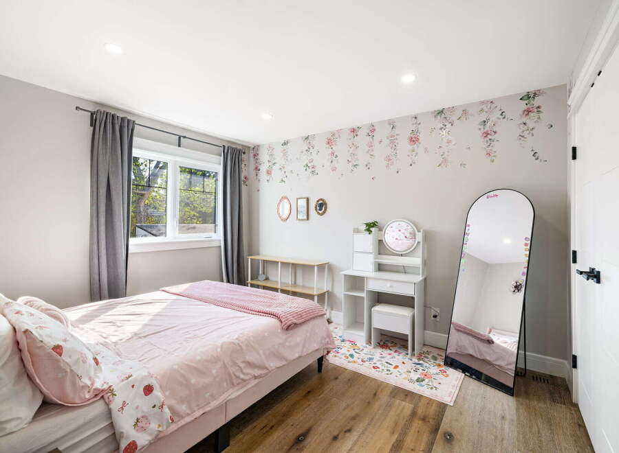 This charming bedroom features a cozy bed with pink strawberry-themed bedding, complemented by elegant floral wallpaper.