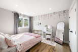 This charming bedroom features a cozy bed with pink strawberry-themed bedding, complemented by elegant floral wallpaper.
