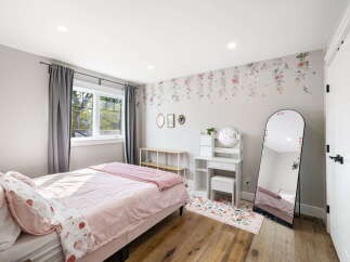 This charming bedroom features a cozy bed with pink strawberry-themed bedding, complemented by elegant floral wallpaper.