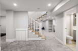 Discover this beautifully finished basement featuring a modern staircase with wood treads and white railings, leading to a spacious living area.