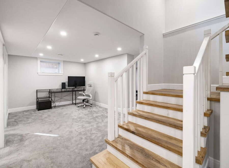 Discover this beautifully finished basement featuring a modern workspace with a sleek desk and ergonomic chair, perfect for productivity.