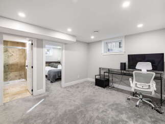 Discover comfortable living in this modern basement suite, featuring a spacious bedroom with a cozy grey duvet and a private ensuite bathroom with a walk-in shower.