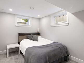 Discover comfortable living in this charming bedroom, featuring a cozy bed with plush grey pillows and a soft blanket.