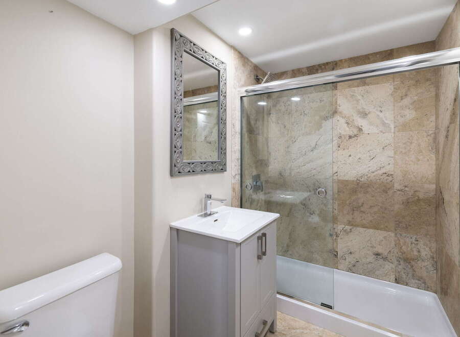 This modern bathroom features a sleek vanity with a white countertop and chrome faucet, complemented by a decorative mirror.