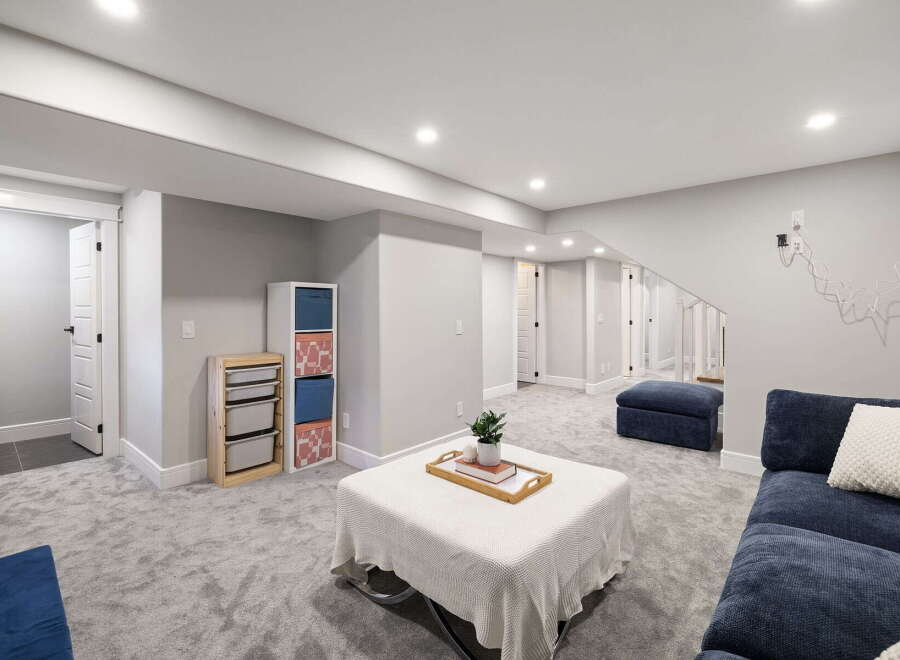 Discover this beautifully finished basement, featuring a spacious living area with plush carpeting and ample storage solutions.
