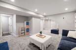Discover this beautifully finished basement, featuring a spacious living area with plush carpeting and ample storage solutions.