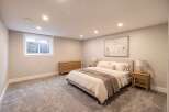 Discover this inviting bedroom featuring a plush king-size bed, complemented by a modern wooden dresser and a sleek nightstand with a lamp.
