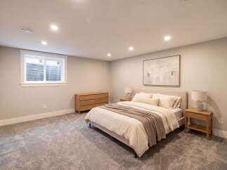 Discover this inviting bedroom featuring a plush king-size bed, complemented by a modern wooden dresser and a sleek nightstand with a lamp.