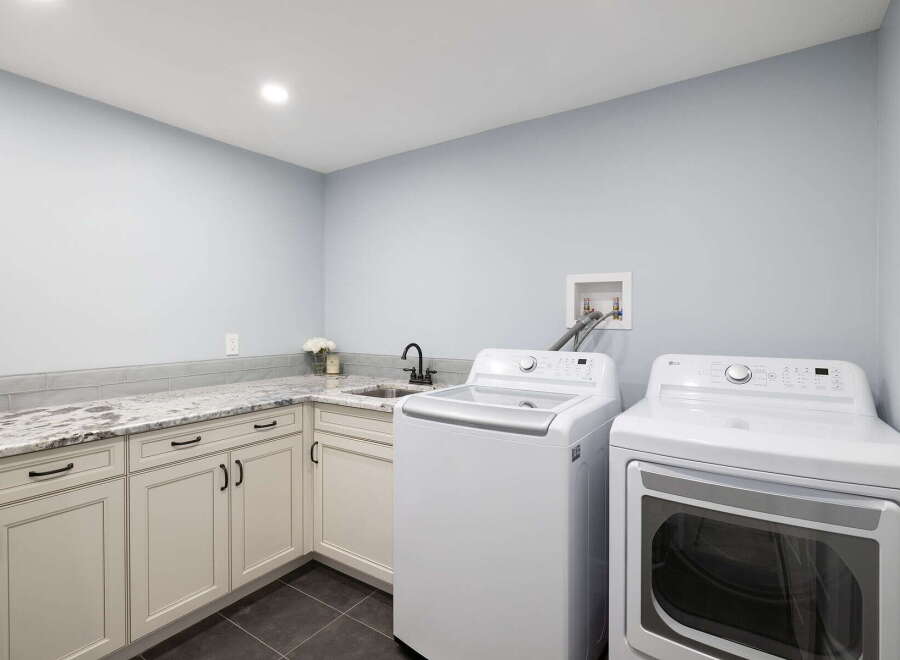 This spacious laundry room features a top-load washing machine and a front-load dryer, perfect for handling large loads.