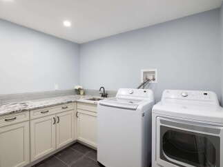 This spacious laundry room features a top-load washing machine and a front-load dryer, perfect for handling large loads.